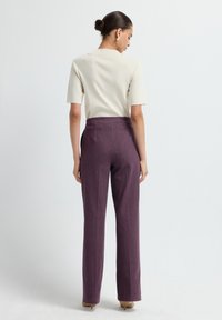 Haut beige clair à manches courtes associé à un pantalon prune taille haute. Le pantalon présente une coupe droite et une texture subtile.