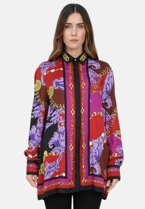 Blusa a maniche lunghe in seta di un vibrante rosso e viola, presenta intricati motivi e catene dorate, con colletto e polsini a camicia neri.