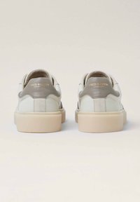 Sneakers in pelle bianca con un accento in suede grigio sul tallone, suola in gomma beige e marchio dorato in rilievo sul retro. Design a punta rotonda.