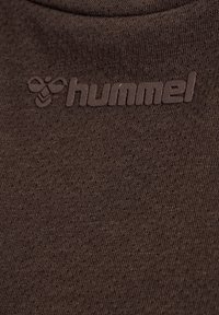 Brun bomullstyg med en subtil textur, prydd med en präglad "hummel"-logotyp och en biikon i mörkbrun.