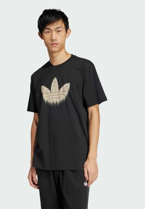 Sort bomulds t-shirt med et falmet, abstrakt grafisk design af Adidas-logoet i en lysere nuance. Rund hals og afslappet pasform.