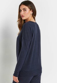 Maglia a maniche lunghe blu navy con scollatura rotonda, vestibilità comoda e texture morbida. Presenta cuciture sulle spalle scese e polsini a costine.
