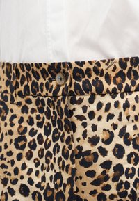 Βαμβακερό παντελόνι με λεοπάρ σχέδιο σε μπεζ φόντο, με μαύρες και καφέ βούλες, διαθέτει κούμπωμα με κουμπί και ζώνη στη μέση.