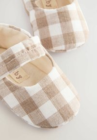 Brune og hvide ternede babysko med en blød tekstiloverdel, afrundet tå og Velcro-strop for en sikker pasform.