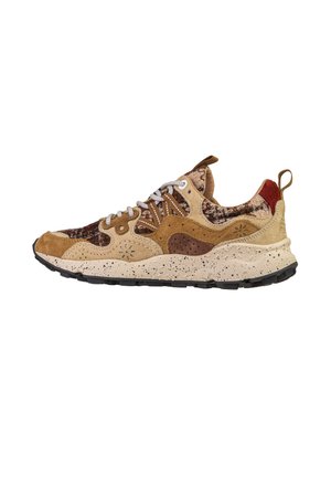 Sneaker marrone e beige con suola bianca screziata, tomaia mista in suede e tessuto, lacci bianchi e linguetta sul tallone su sfondo bianco.