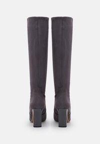 Bottes grises montantes jusqu'au genou, en matériau lisse avec un talon carré et des coutures nettes, conçues pour une silhouette ajustée.