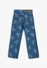 Vaqueros de mezclilla azul con un patrón floral, diseño de pierna recta, cinco bolsillos y una etiqueta de cuero marrón en la cinturilla.