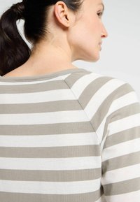 Gestreifter Pullover mit Rundhalsausschnitt, der abwechselnd in hellgrau und Weiß gestreift ist, aus weichem Stoff gefertigt; Raglanärmel-Design.