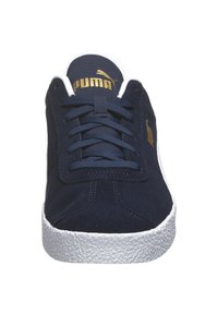 Zapatilla de ante en color azul marino con suela de goma blanca, diseño de cordones y logo dorado de Puma en la lengüeta y el lateral. Punta texturizada y costuras sutiles.