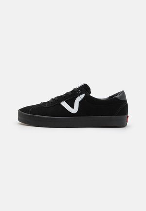 Sort lavtop sneaker med sort sål, hvidt sidelogo, sorte snørebånd og en rød mærkat på hælen, vist fra ydersiden.