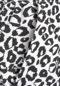 Black and white leopard print fabric with a textured surface, featuring irregular shapes and patterns on a lighter background.