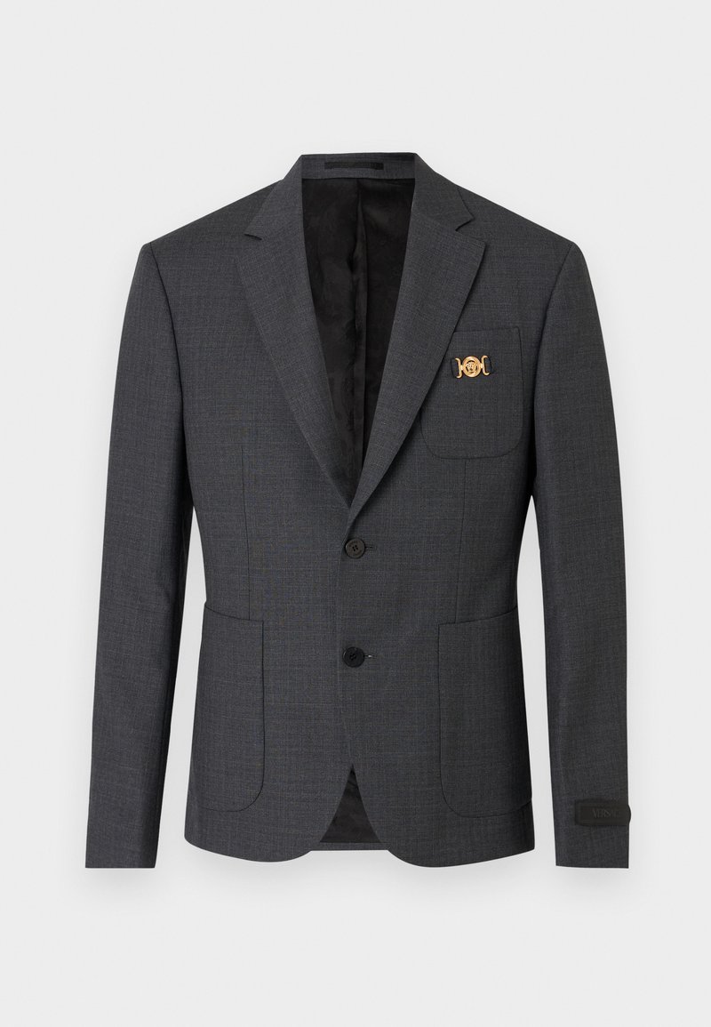 Blazer gris foncé ajusté avec deux poches avant à rabat, deux boutons noirs, col à encoches et épingle décorative dorée sur la poche poitrine.