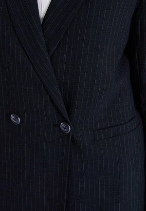 Veste de costume bleu marine à rayures, fabriquée en tissu texturé, avec deux boutons, une poche à rabat et des rayures verticales marquées.