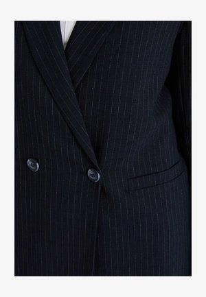 Veste de costume bleu marine à rayures, fabriquée en tissu texturé, avec deux boutons, une poche à rabat et des rayures verticales marquées.