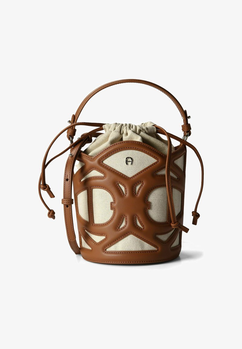 Sac bourse en cuir marron avec un intérieur en toile crème, fermeture par cordon et design découpé. Doté d'une poignée courte et d'une bandoulière ajustable.