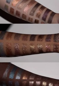 Een close-up van drie armen die verschillende oogschaduwswatches op de huid tonen, met metallic en glitter afwerkingen in een verscheidenheid aan kleuren en texturen.