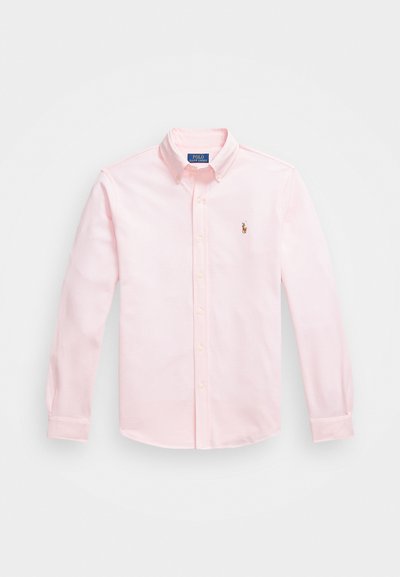 Svetlo roza bombažna srajca s kravato, dolge rokave in vezenim logotipom na levi strani prsnega dela.