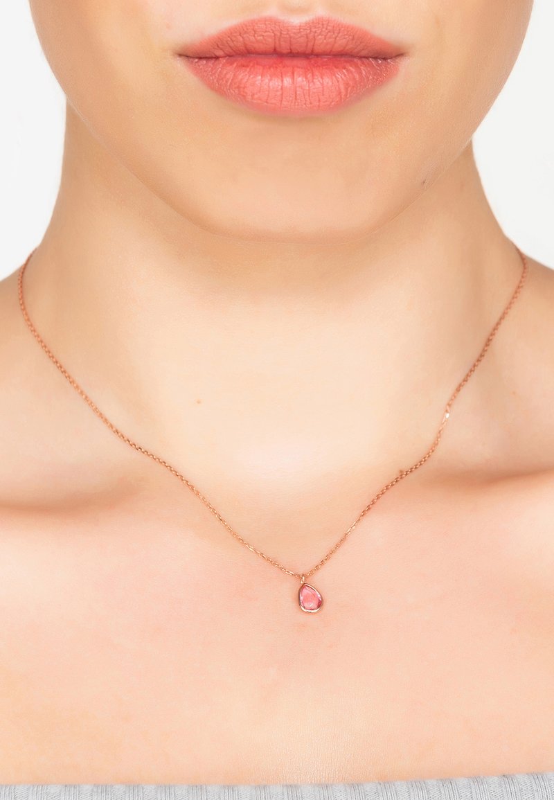 Rózsaarany nyaklánc finom lánccal és csepp alakú rózsaszín drágakő medállal, sima felülettel és diszkrét fényléssel.
