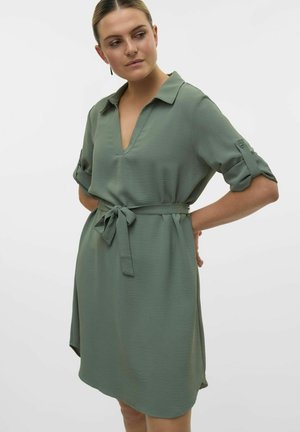 Green, knee-length shift dress made of lightweight fabric. Features a V-neck, rolled sleeves, and a tied waist belt for adjustable fit.
