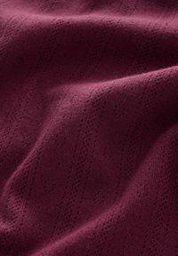 Tessuto a maglia bordeaux con un motivo testurizzato di righe verticali e piccoli dettagli in pizzo, caratterizzato da una trama liscia e morbida.
