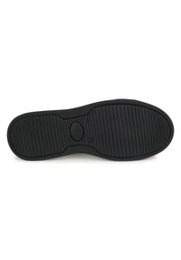 Suela de zapato de goma negra con ranuras horizontales y verticales para tracción, y un inserto ovalado liso en el centro.