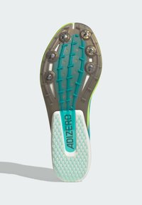 Adizero löparsko skoinnersula med en klar, strukturerad gummiyta och sex metallspikar, med gröna accenter och en ljusblå mittensektion.