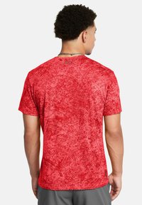 Camisa roja de manga corta con un patrón texturizado, que presenta un escote redondo y un dobladillo ligeramente curvado. La tela parece ligera y transpirable.
