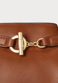 Barna bőr kézitáska arany kapcsoló záró mechanizmussal és lánc részletekkel, sima textúrával és minimalista dizájnnal.