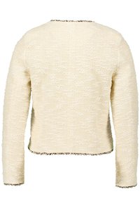 Cremfarbener, kurzer Pullover mit einem strukturierten, gewebten Design. Verfügt über lange Ärmel und ausgefranste Kanten an den Bündchen und am Saum.