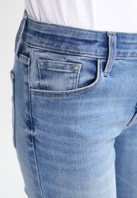 Jeans de mezclilla azul claro con un corte ajustado, que cuentan con un bolsillo frontal, costuras en contraste y un ligero desgaste para aportar textura.