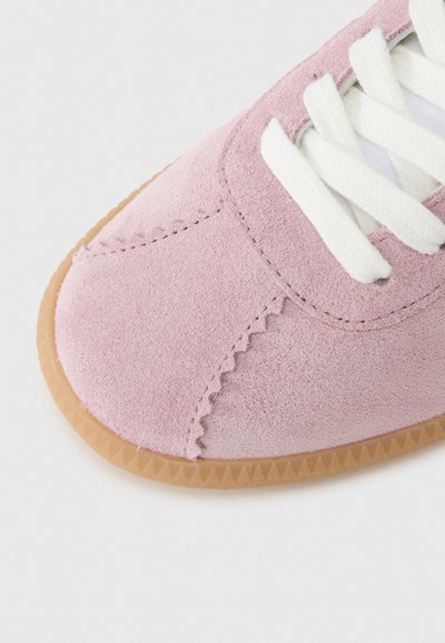 Ροζ αθλητικό παπούτσι από σουέντ με λευκά κορδόνια, διαθέτοντας σ τρογγυλεμένη μύτη, διακριτικές ραφές και υφασμένο σόλα από καουτσούκ χρώματος καραμέλας.