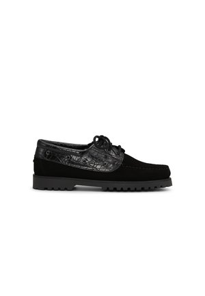 Mocassin en cuir noir avec laçage à l'avant, motif crocodile texturé sur le dessus et les côtés, et semelle en caoutchouc rainurée.