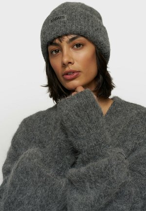 Beanie grigio a maglia e pullover oversize realizzati in materiale morbido e soffice. Il berretto presenta un'etichetta con logo; il pullover ha maniche larghe e strutturate.
