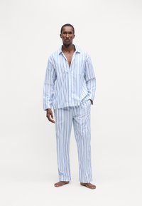 Set de pijamale din bumbac cu dungi, care include o cămașă cu nasturi, guler și mâneci lungi, asortată cu pantaloni în albastru deschis și alb.