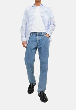 Lichtblauwe gestreepte shirt over een wit T-shirt, gecombineerd met rechte blauwe jeans en zwarte instappers. Casual outfit met een eenvoudig ontwerp.
