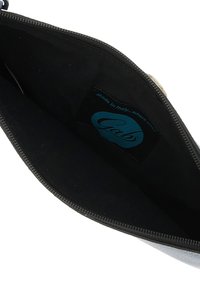 Tessuto interno nero di un sacchetto con chiusura a zip. Presenta un'etichetta blu con la scritta "Gabs." Texture liscia con forma rettangolare.