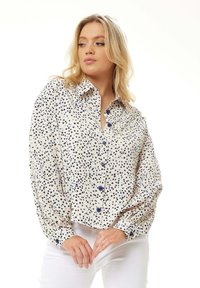 Long-sleeve button-up shirt in cream with blue heart print and blue buttons. Features a collared neckline and loose fit.
