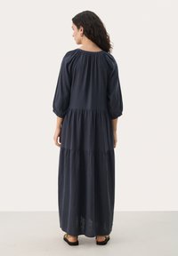 Navy blue, warstwowa sukienka maxi z długimi bufkami i okrągłym dekoltem. Wykonana z lekkiego materiału, z luźną strukturą.