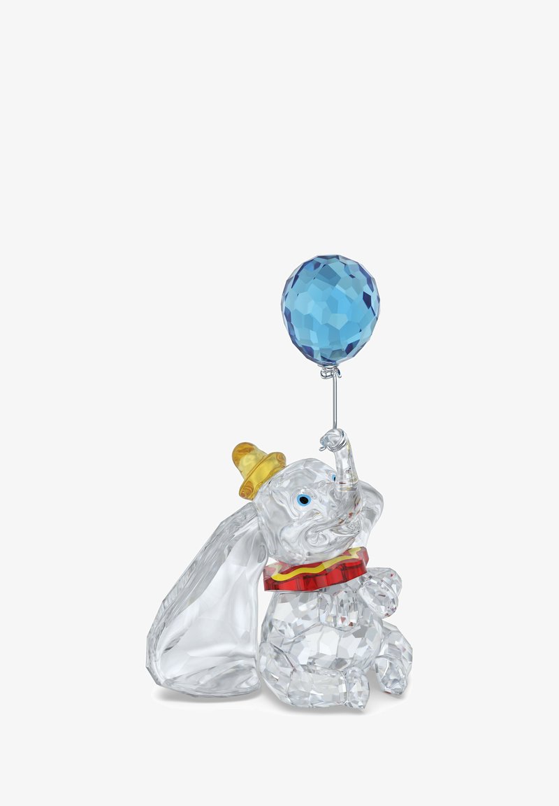 Figurka słoniowa z kryształu z żółtym kapeluszem i czerwonym kołnierzykiem, trzymająca niebieski, fasetowany balon, z przezroczystymi i wypolerowanymi powierzchniami.
