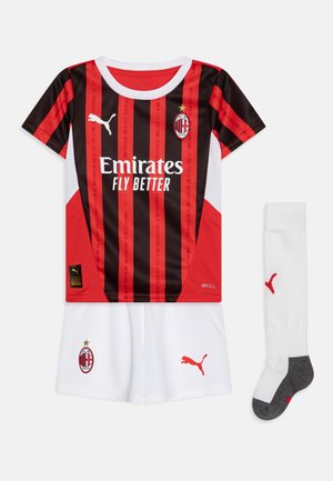 Kit da calcio giovanile dell'AC Milan con una maglia a righe rosse e nere, pantaloni bianchi e calze bianche abbinate con accenti grigi. Logo Puma visibile.
