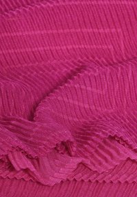 Fuchsia tekstureret stof med ribbet mønster, der viser en blød, let vævning og subtile vandrette linjer langs overfladen.