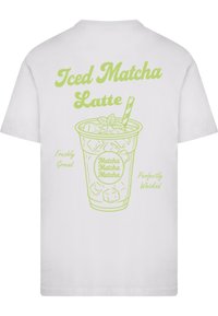 Bílá tričko s grafickým motivem zeleného ledového matcha latte, s textem zdůrazňujícím "Ledové Matcha Latte," "Čerstvě Mleté" a "Dokonale Ušlehané."