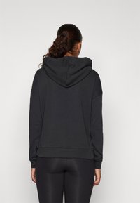 Hoodie preto com um corte descontraído, capuz grande e mangas longas. Feito de tecido macio, com uma textura suave e uma bainha canelada.