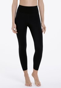 Black leggings with a high waistband, made of stretchy material. Features a smooth texture and fitted silhouette, designed for comfort and movement.