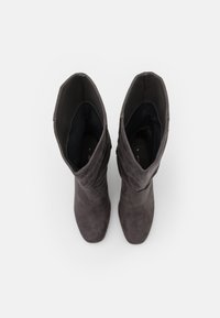 Bottes en daim jusqu'aux genoux de couleur gris foncé ; bout effilé, texture douce et design replié en haut, avec doublure intérieure noire.