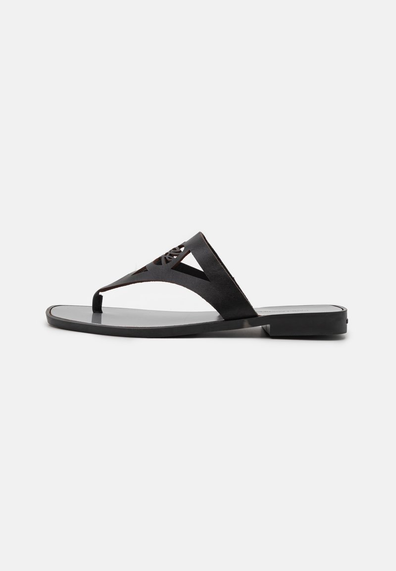 Svarta läder flip-flop sandaler med en tunn remdesign och utskärningsmönster, platt sula och minimalistisk siluett.