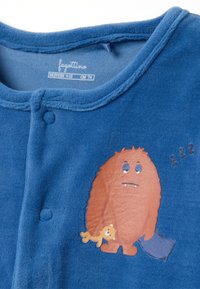 Pijama de felpa azul con un gráfico de un monstruo marrón sosteniendo un osito de peluche amarillo. Tiene cuello redondo y cierre de botones a presión. Textura suave.