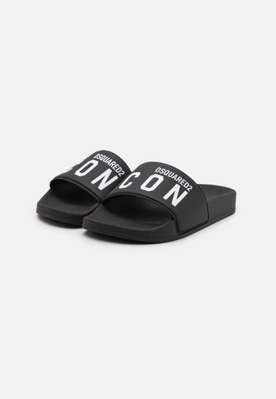 Schwarze Riemchensandalen mit strukturiertem Sohle, die einen breiten Riemen mit auffälliger weißer Schrift "DSQUARED2 ICON" zieren. Minimalistisches Design.