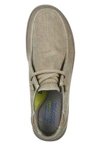 Zapato de lona color tostado con punta redondeada, diseño con cordones y interior acolchado. Superficie texturizada con costuras visibles y logo en la plantilla.