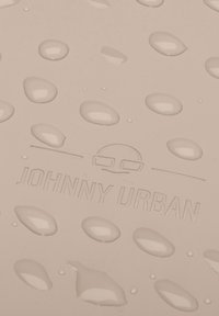Világos bézs felület vízcseppekkel, amelyen egy domború "JOHNNY URBAN" logó található, minimalista dizájnnal. Simaszövet.